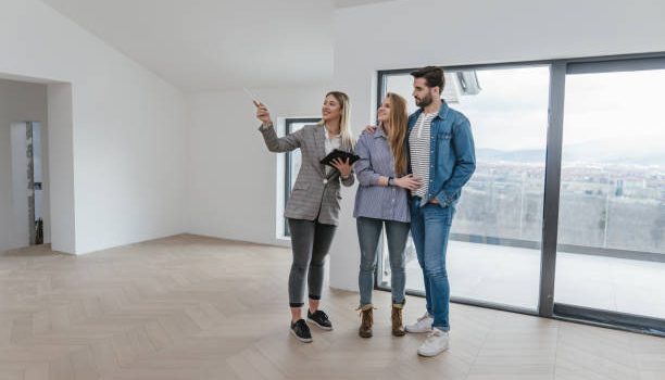 Beautiful young couple buying an apartment with a help of a real estate agent.